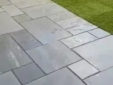 Grey Indian stone patio laid in a mixed-size pattern beside a lawn