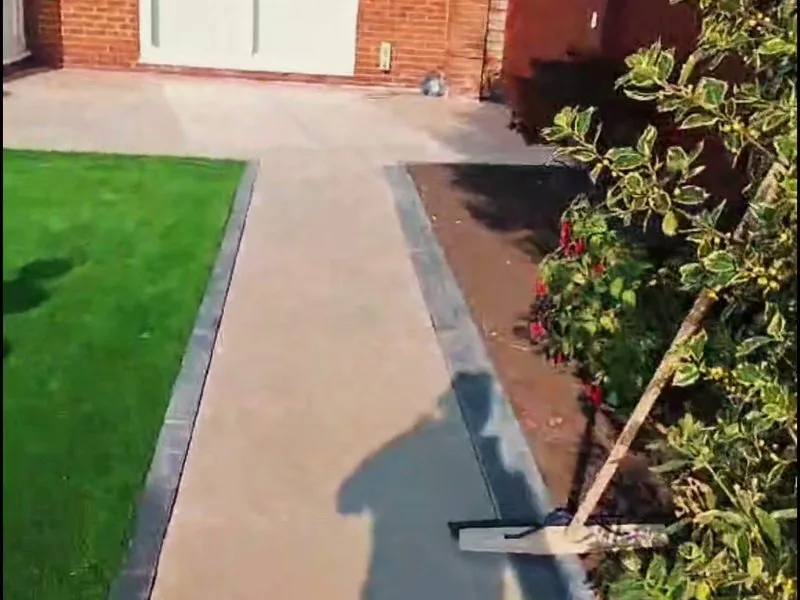 Buff garden path with charcoal block edging beside a new lawn and planted border