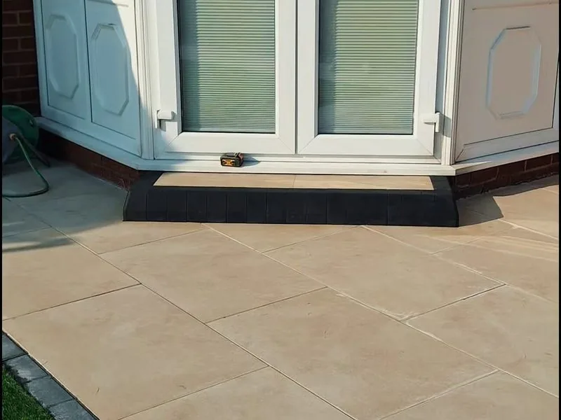 Buff porcelain patio with charcoal block edging and a step outside conservatory french doors