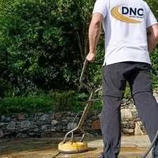A DNC Block Paving fitter pressure washing a stone patio