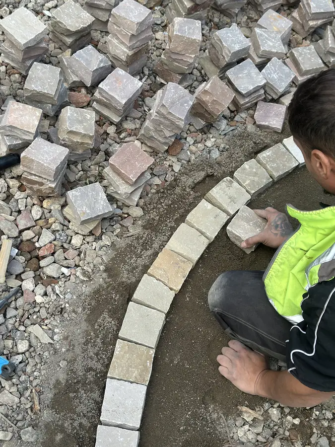 Setts being laid one by one along the curve of the ring, with loose stone around them