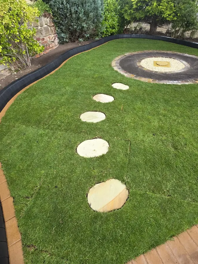 A new lawn with round stepping stones leading up to a block-edged circle at the top of the garden