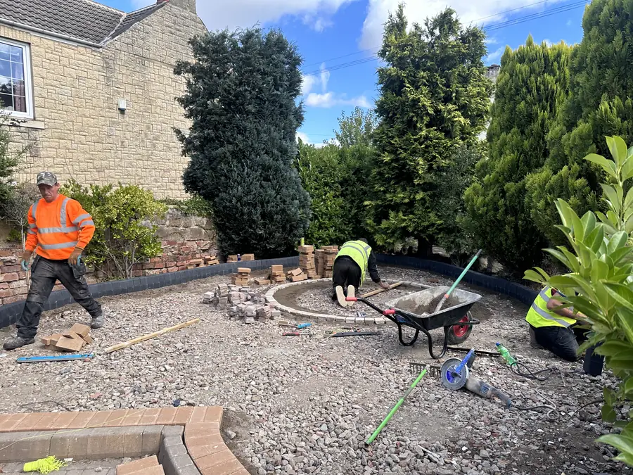 A stripped back garden covered in compacted crushed stone, with a curved kerb line marking out a circle