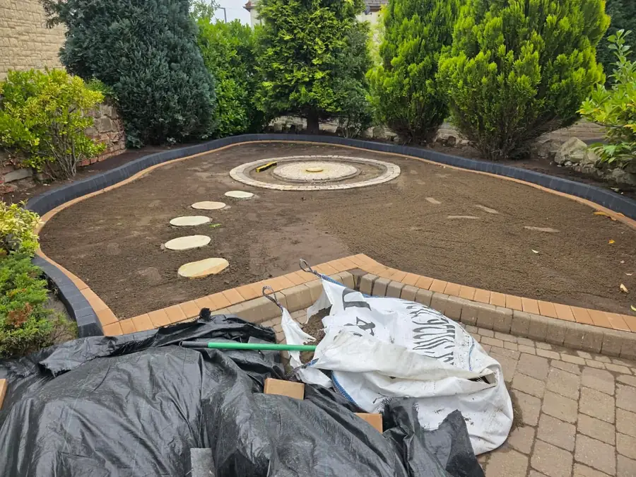 The inside of the block-edged circle filled with levelled soil, three round stepping stones and a central stone base
