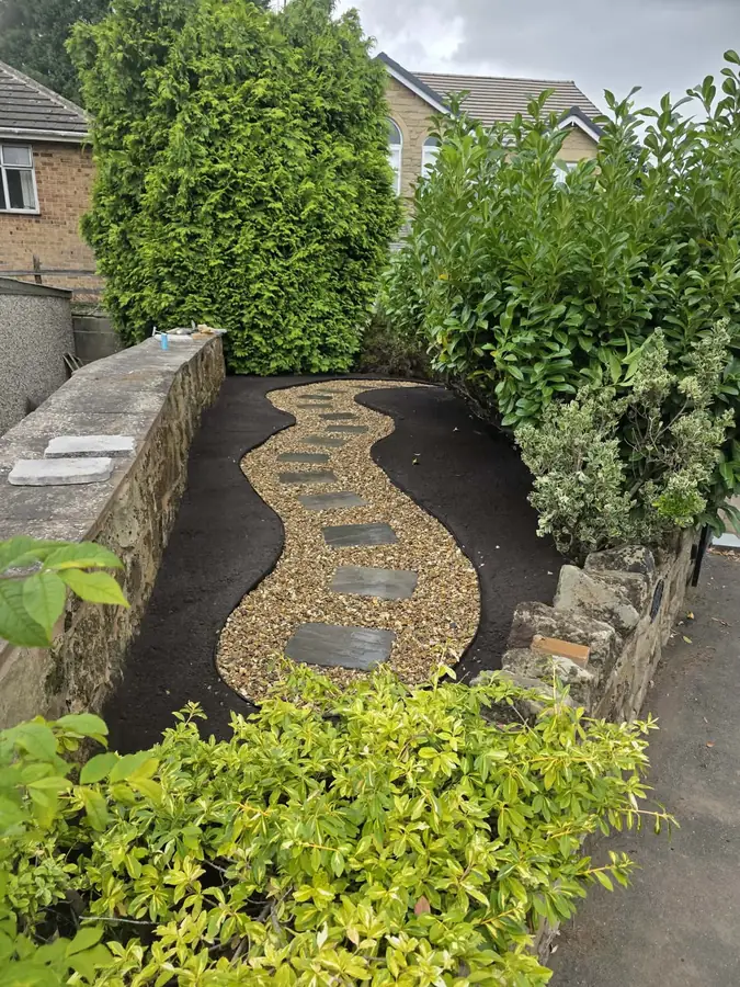 A winding gravel path with stepping stones between beds of bare soil, seen from the top of the strip